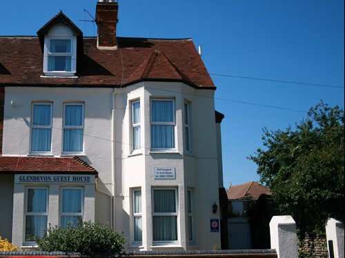 White three storey guest house with large windows and tiled roof